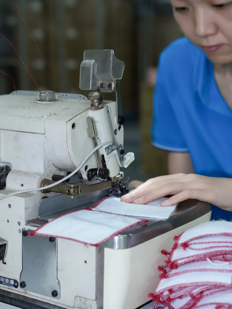 Drawstring Pouch Factory Production Process factory worker sewing drawstring pouch channel on industrial machine