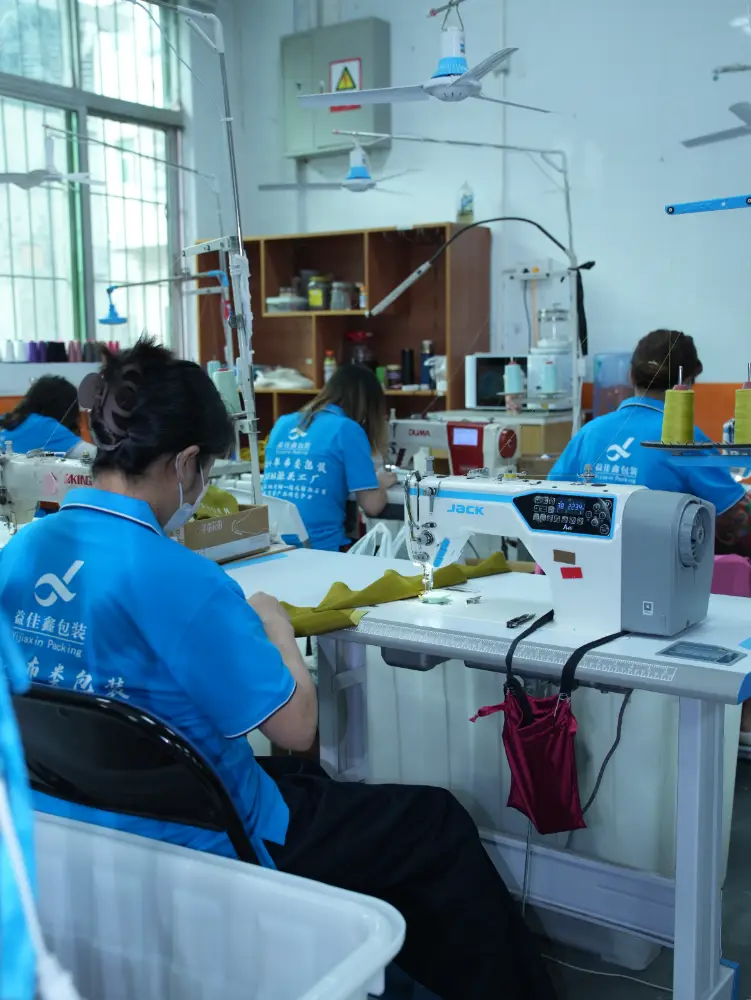 Fabric Pouch Sewing Workshop Workers sewing fabric pieces at industrial sewing machines in a garment packaging workshop
