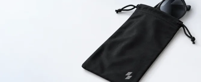 Black custom sunglasses pouch concept with drawstring closure, black sunglasses and an abstract front emblem.