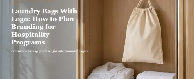 Natural cotton hotel laundry bag hanging in a guest wardrobe beside a robe and folded towels